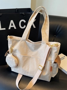 Minimalist cream corduroy tote bag with multiple pockets and small coin purse on a sofa