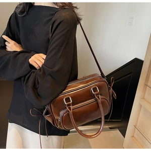 Detail view of a vintage dark brown bowling bag with silver zippers and stylish tassels