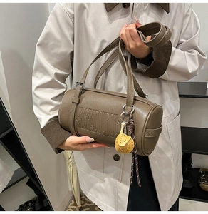Detail of vintage textured leather cylinder bag with star embossing and puffer charm