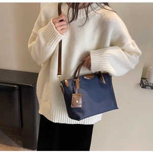 Detail view of large dark blue oxford tote bag with brown leather handles and shoulder strap