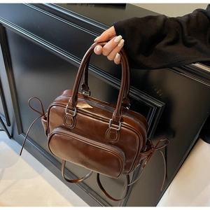 Detail of vintage brown bowling bag with glossy finish and side ribbon bow accents