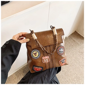 Close-up of vintage brown leather handbag with retro patches and rope handles
