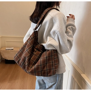 Detailed side view of a large brown plaid tote bag with adjustable shoulder strap