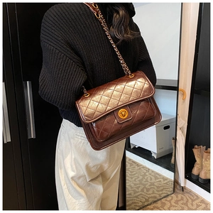Detail of a dark brown quilted chain bag with a metallic rotary lock and glossy finish
