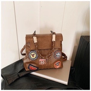Macro detail of vintage brown PU leather bag with embroidery patches and rope handles