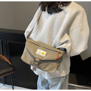 Dettaglio della borsa messenger in nylon verde oliva con etichetta TR-9 e zip arancione