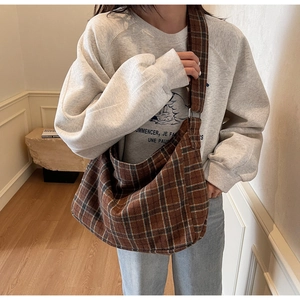 Detail of the wide shoulder strap on a brown checkered hobo tote bag for daily commute
