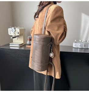 Detail of vintage brown cylinder bag with embossed text and baseball keychain accessory