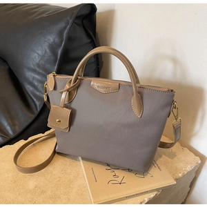 Detail of coffee brown oxford fabric crossbody bag with leather trim and gold hardware
