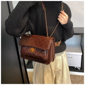 Detail of a brown quilted leather shoulder bag with gold chain strap and turn-lock