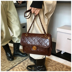 Detailed view of dark brown quilted leather bag with golden twist lock and chain strap