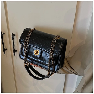 Close-up of black quilted leather shoulder bag featuring a gold chain and circular metal lock