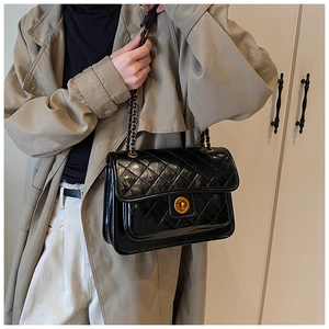 Detailed view of black quilted leather shoulder bag with golden round twist lock
