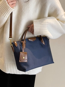 Minimalist navy nylon handbag with brown leather trim shown in a lifestyle photo