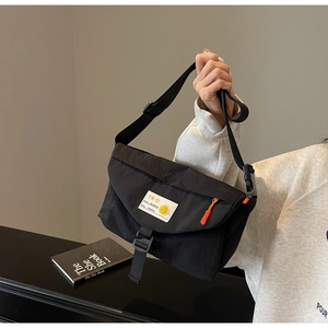 Dettaglio della borsa a tracolla in nylon nero con etichetta smiley e cerniere arancioni