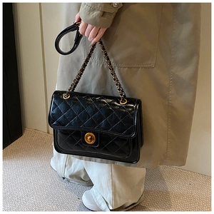 Detail of black quilted leather shoulder bag with gold twist lock and chain strap