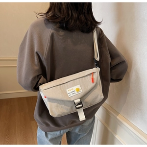 Dettaglio della borsa a tracolla bianco avorio con patch smiley e cinturino regolabile