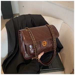 Detail of dark brown quilted leather bag with gold chain strap and metallic closure