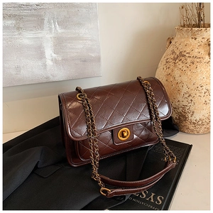 Detail of dark brown quilted leather shoulder bag with golden chain and twist lock