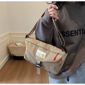 Dettaglio della borsa a tracolla in nylon kaki con patta e chiusura a fibbia in plastica
