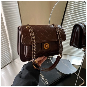 Detail of dark brown quilted leather bag with gold chain strap and twist-lock closure