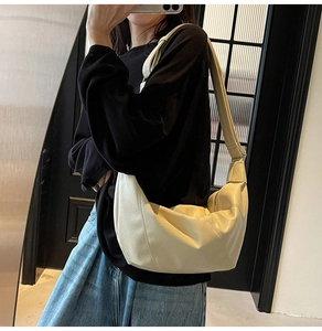 Dettaglio di una borsa a mezzaluna in morbida pelle color crema con tracolla larga