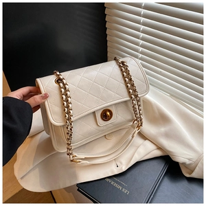 Detail of white quilted texture leather and vintage gold chain on a crossbody flap bag