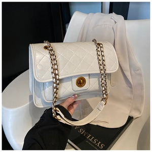 Close-up of white quilted crossbody bag with gold twist lock and woven chain strap