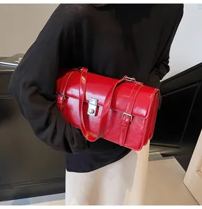 Détail d'un sac cartable rouge vintage en cuir ciré avec boucle argentée porté par un mannequin
