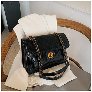 Close-up of black quilted chain bag featuring a gold twist lock and glossy faux leather