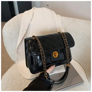 Close-up of black quilted shoulder bag featuring gold twist lock and chain strap detail