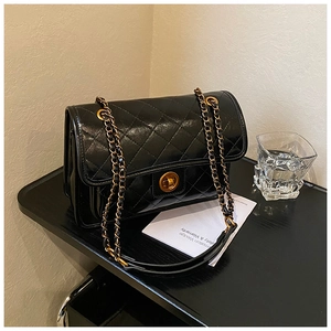 Detailed close-up of quilted black leather texture and golden twist-lock on shoulder bag