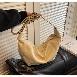 Dettaglio della borsa a mezzaluna beige con trama a grana fine e chiusura a zip