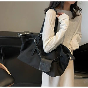 Dettaglio borsa tote in nylon nero con fibbie argentate regolabili e pochette laterale
