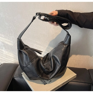 Dettaglio della texture in pelle nera morbida e della chiusura a zip della borsa hobo