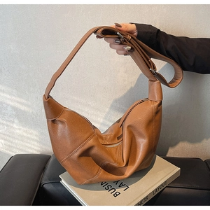 Dettaglio borsa hobo in morbida pelle marrone con tracolla regolabile e fibbia metallica