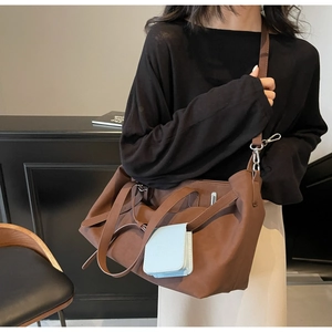 Dettaglio di una grande borsa tote marrone scuro con una piccola pochette decorativa azzurra sul lato