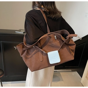 Dettaglio di borsa tote in pelle opaca marrone scuro con ciondolo decorativo blu chiaro