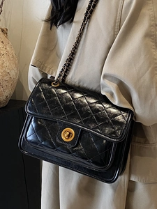 Chic black quilted chain crossbody bag with golden clasp shown on a shoulder