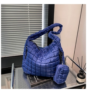Detailed macro view of navy blue quilted puffer tote bag with matching mini pouch set