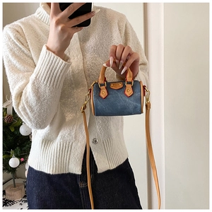 Mini sac polochon en denim avec poignées en cuir marron porté en bandoulière