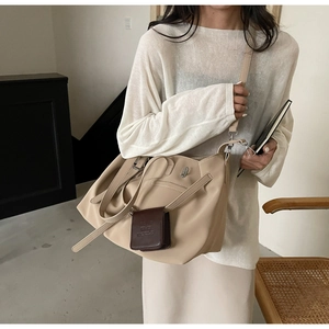 Dettaglio della grande borsa a spalla beige opaca con mini pochette marrone decorativa