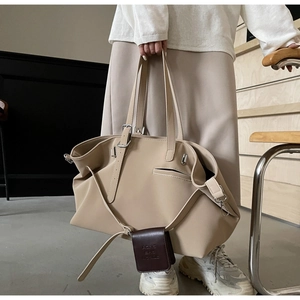 Dettaglio della borsa tote minimalista in pelle beige con pochette marrone e fibbie metalliche