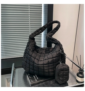 Detail view of black quilted puffer bag with matching small round pouch on a metal cart