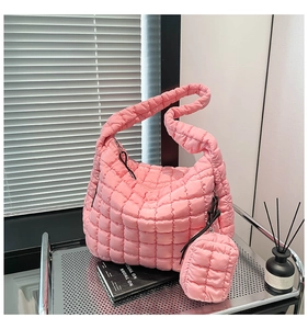 Detail of pink quilted puffer shoulder bag with matching mini pouch on metal stand