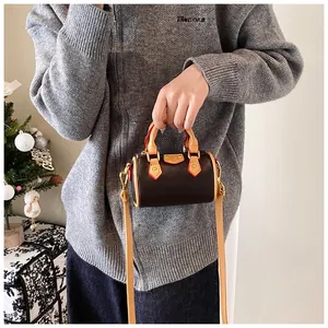 Détail du mini sac Boston avec bordure rouge contrastée et finitions métalliques dorées
