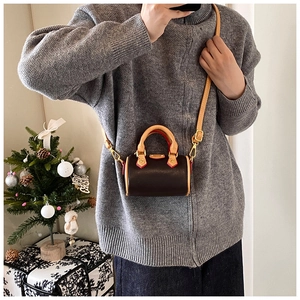 Détail d'un mini sac cylindre marron bicolore avec détails dorés porté en bandoulière