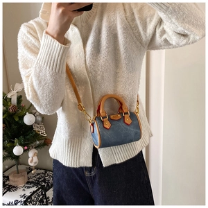 Détail du mini sac Boston en denim et cuir marron avec coutures rouges et boucles en métal