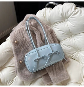Detail of light blue glossy patent leather shoulder bag featuring two sweet bow decorations
