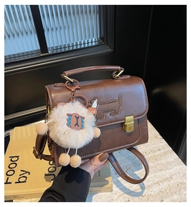 Close-up of brown leather handbag with gold rotating lock and dog pattern embroidery